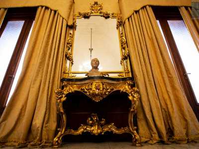 Una parete � occupata da due alte porte-finestre e una consolle settecentesca con specchiera intagliata a mano... 